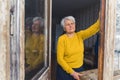 Old caucasian retired gray-haired woman staring out the open balcony door on a winter day Royalty Free Stock Photo