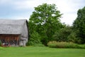 Old cedar sided country barn with red wheel carriage in front of Royalty Free Stock Photo