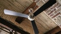 Old ceiling fan lamp spinning in the antique interior with brick walls and wooden roof Royalty Free Stock Photo