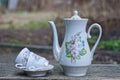 an old ceramic service of a white teapot with two cups and a plate with a color pattern Royalty Free Stock Photo