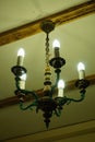 Old chandelier with five lamps hangs on the ceiling with a pre-revolutionary house.