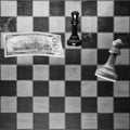 Old chess board with vintage figures of king and queen and money in us dollars. Concept of research problems in economics, money