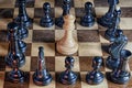 Old chess on a wooden board - a white figure queen surrounded by black