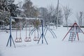 Old children playground, slides and swings, in a park covered in snow in Serbia, in Eastern Europe, during a freezing dark evening Royalty Free Stock Photo