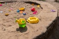 an old children's outdoor sandbox with a children's watering can in the foreground and a bunch of forgotten toys Royalty Free Stock Photo