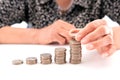 An old Chinese lady is stacking a row of dollar coins