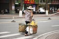 Old chinese woman people street vendors bearing hawker basket walking on beside road and traffic at Shantou or Swatow, China