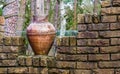 Old chipped roman vase on a brick wall, outdoor garden decorations and architecture Royalty Free Stock Photo