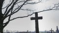 Old christian cross in a cemetery on a background of trees branches and light sky. Cemetery concept. Royalty Free Stock Photo