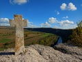 Old Christian stone cross. Beautiful landsaft of rocky hills that is crossed by a meandering river. Sunny day with blue sky with