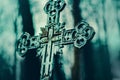 An old Christian tombstone cross stands at dusk in the cemetery, and rosaries hang on it. Death. Religion