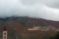 Old church over mountains with red plants and clouds in misty rainy day Royalty Free Stock Photo