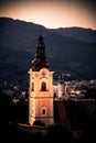 Old church tower with a clock in front of an austrian city at sunset Royalty Free Stock Photo