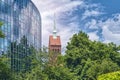 Church tower next to a modern office house, covered by trees Royalty Free Stock Photo