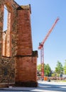 Old church walls and construction crane. Construction next to the church. City infrastructure. Under the blue sky. Royalty Free Stock Photo