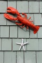 Old clapboard shingles on home`s exterior with lobster and starfish decorations