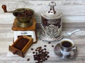 An old classic coffee grinder, silver coffee jar, a cup of coffee, porcelain spoon, coffee beans and minced coffee. Retro style.