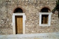 Old classic little church arch door and window frame on earth tone natural stone wall facade background with marble curb in front Royalty Free Stock Photo