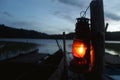 Old classic oil lantern of fisherman hanging on a wood with wooden fishing boats and blue sky over the lake in the early morning Royalty Free Stock Photo