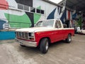 Old classic red and white 1980s Ford F 100 V8 pickup truck on a colorful industrial background. Royalty Free Stock Photo