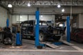 An old classic retro car of black color stands on a blue lift for repair, restoration and restoration in a vehicle maintenance and