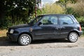 Old classic small cheap popular black compact car Nissan Micra parked left side view