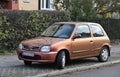 Old classic small rusty cheap popular metal red compact car Nissan Micra parked left side viewrusty