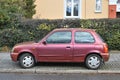 Old classic small rusty cheap popular metal red compact car Nissan Micra parked left side viewrusty