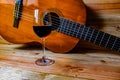 Old classical guitar on wooden background and a glass of wine Royalty Free Stock Photo