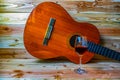 Old classical guitar on wooden background and a glass of wine Royalty Free Stock Photo