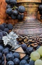 Old clay wine jug surrounded by black grape bunches and winemaking emblem