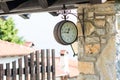 Old clock hanging on the wall in the village at platamonas