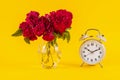 Old clock and red rose flower in vase on yellow background Royalty Free Stock Photo