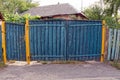 Rural blue wooden fence and closed doors on the street near the road Royalty Free Stock Photo