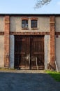 Old closed rustig barn gates in red brick wall. Rural door in sunset light. Royalty Free Stock Photo