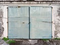 Old, closed and rusty metal double door on corroded concrete wall. Architecture and construction in the French West Indies Royalty Free Stock Photo