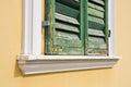 Old closed and weathered wooden window against a plaster wall with damaged green shutter Royalty Free Stock Photo