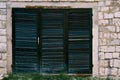 An old closed window in black with a blue tint with blinds on a brick wall. Royalty Free Stock Photo