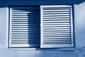 Old closed window with classic blue shutters on a blue wall background Royalty Free Stock Photo