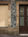 Old closed window with wooden shutter and a door with translucent glass in a granite stone wall and blue tiles Royalty Free Stock Photo