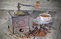 Old coffee grinder with coffee beans and cup of coffee Royalty Free Stock Photo