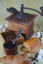 Old coffee grinder, cup, spoon and sugars. Chocolate bread and croissant Royalty Free Stock Photo