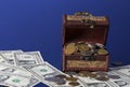 Old coins in chest with dollar bills on blue background with reflections Royalty Free Stock Photo