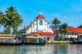 Old colonial Saint Thomas catholic church on the coast of Pamba river, with palms and anchored houseboats, Alleppey, Kerala, South Royalty Free Stock Photo