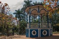 Old and colorful gazebo in a small square amid verdant garden full of trees, in a sunny day at SÃÂ£o Manuel.