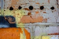 Old orange blue black paint with cracks on red brick wall as background, texture, selective focus Royalty Free Stock Photo