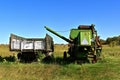 Old combine and grain truck parked in an overgrown meadow