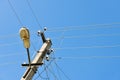 Old concrete electric pole for transmission of wired electricity with lamp post on a background of a cloudy blue sky. Obsolete me Royalty Free Stock Photo