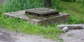 An old concrete manhole with a metal cover in the green grass