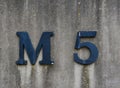 Old concrete wall attached with blue M5 letter